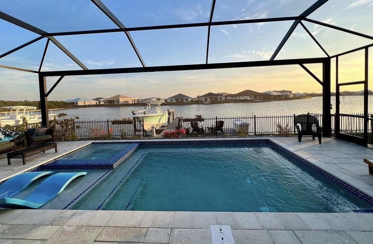Pool and spa under a screen enclosure overlooking a Florida waterway at sunset