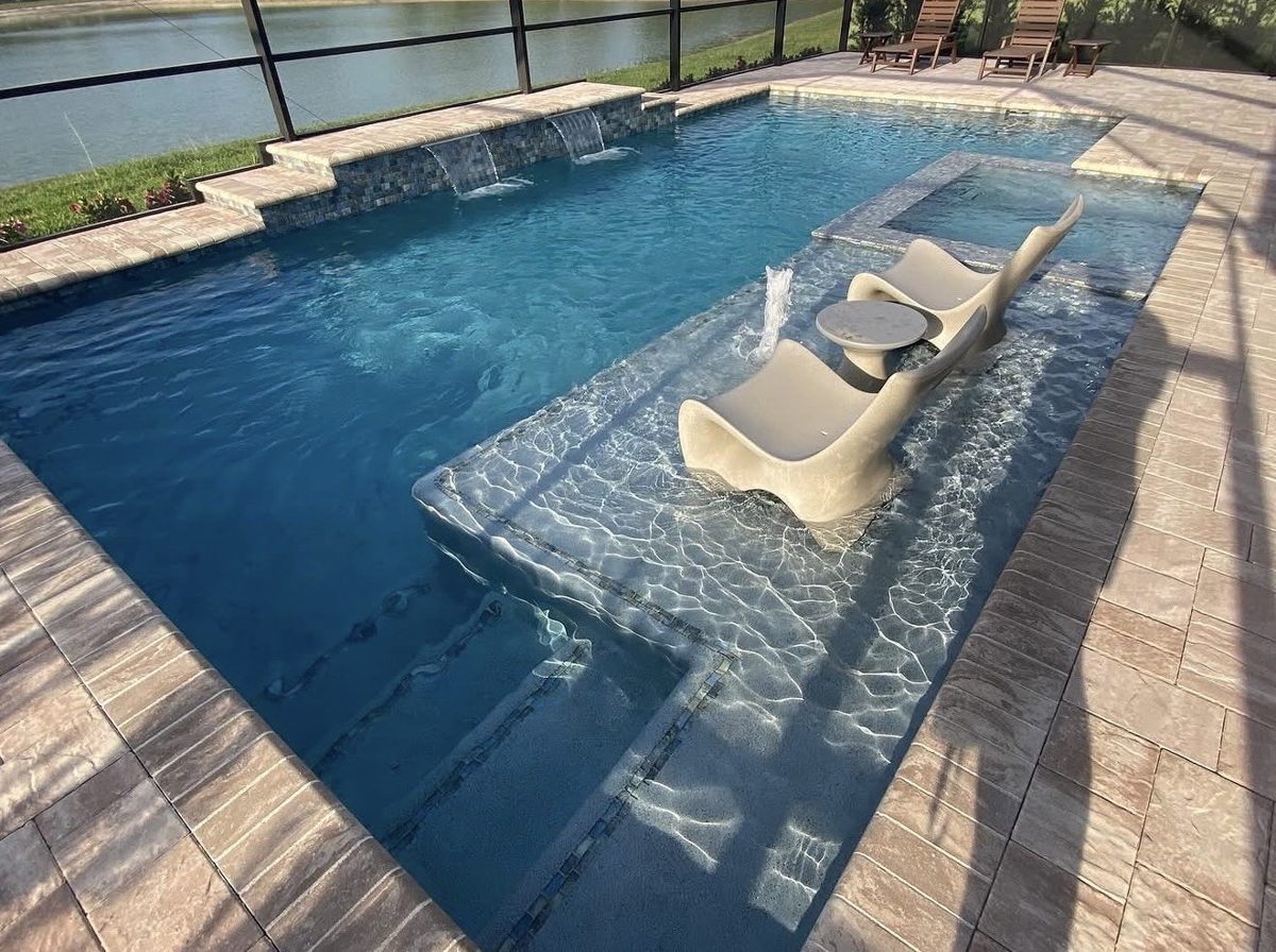 Pool with tanning ledge, lounge chairs, spa and waterfall features